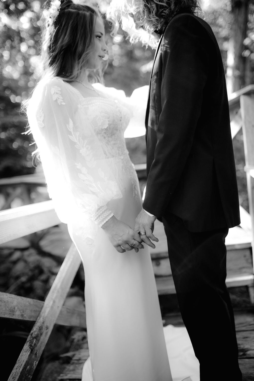 Side view of couple in wedding attire standing together on outdoor deck.
