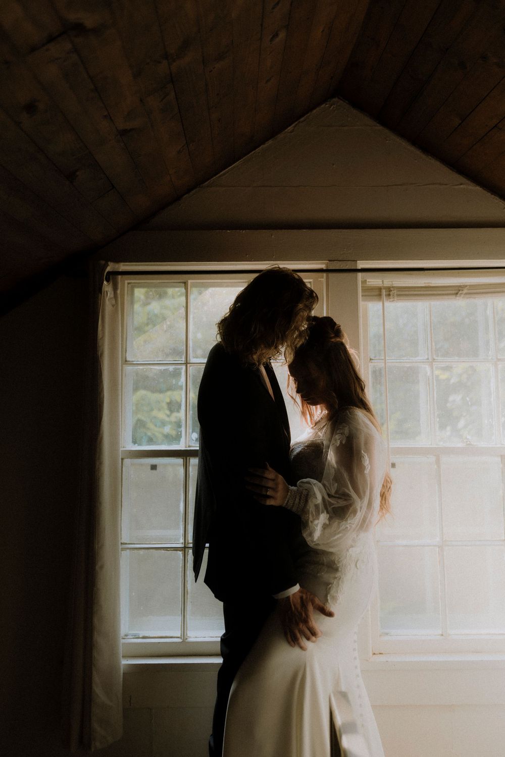 A tender moment by a window in warm natural light.