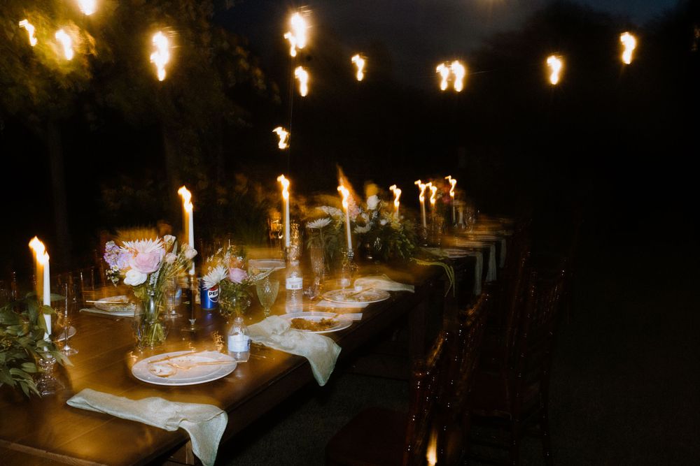 A romantic evening wedding reception table illuminated by hanging string lights.