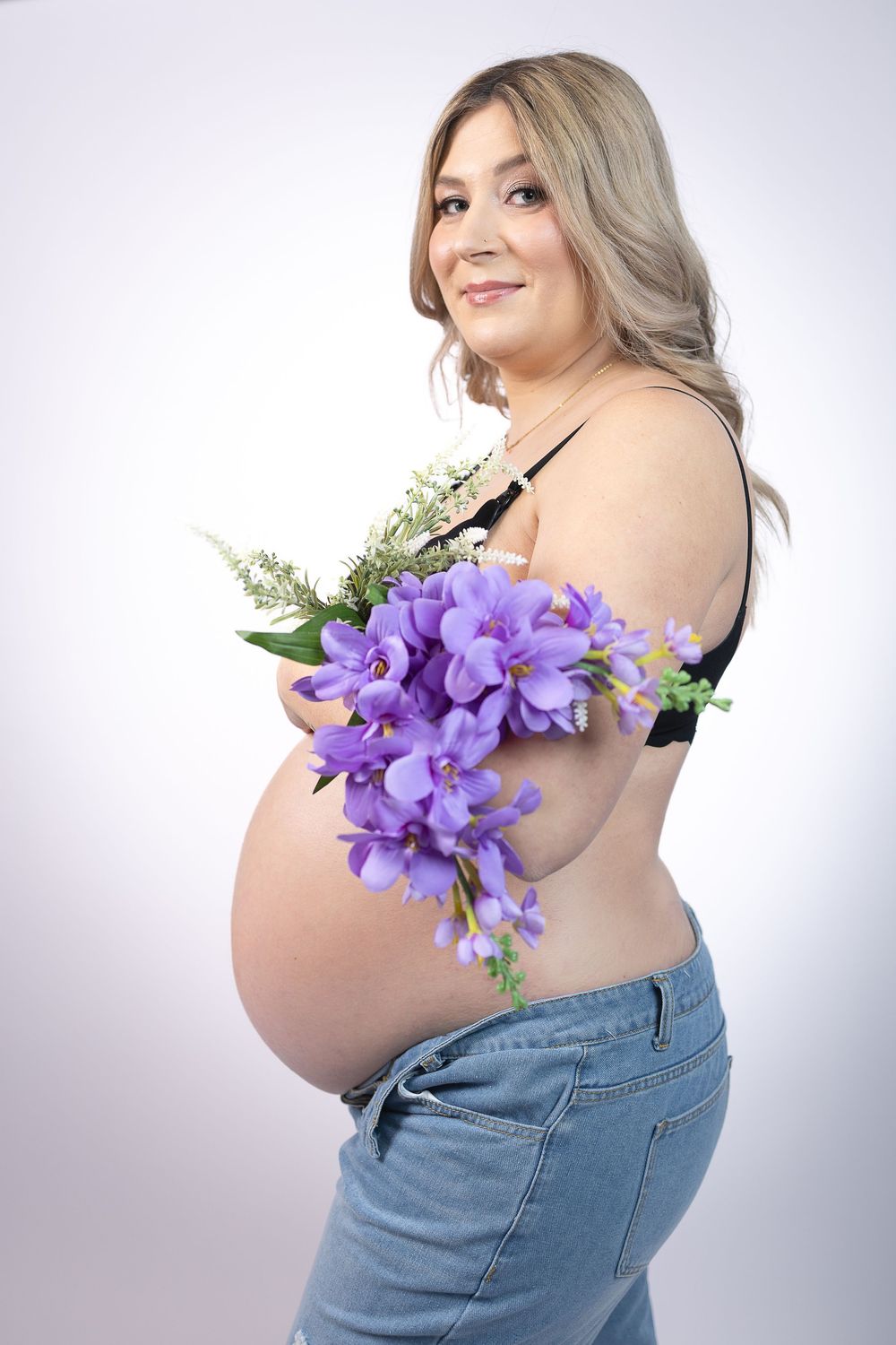 Four artistic maternity photos showing a pregnant woman in denim with purple iris flowers against a light background.