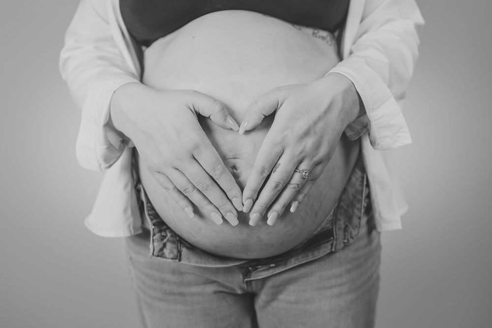 A series of black and white cropped photos showing a pregnant belly being held by hands at different angles.