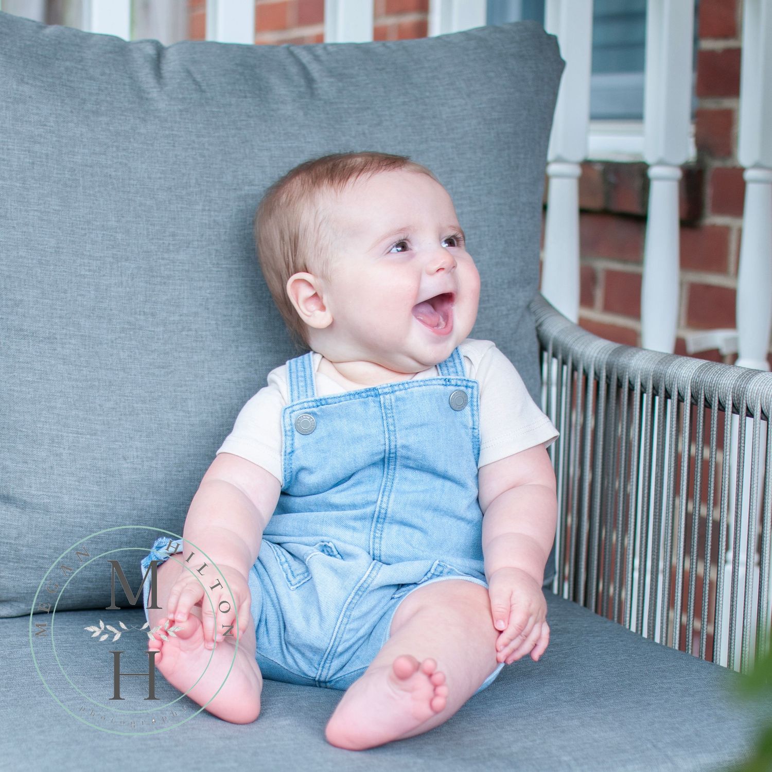 Little boy in overalls smiling off to side