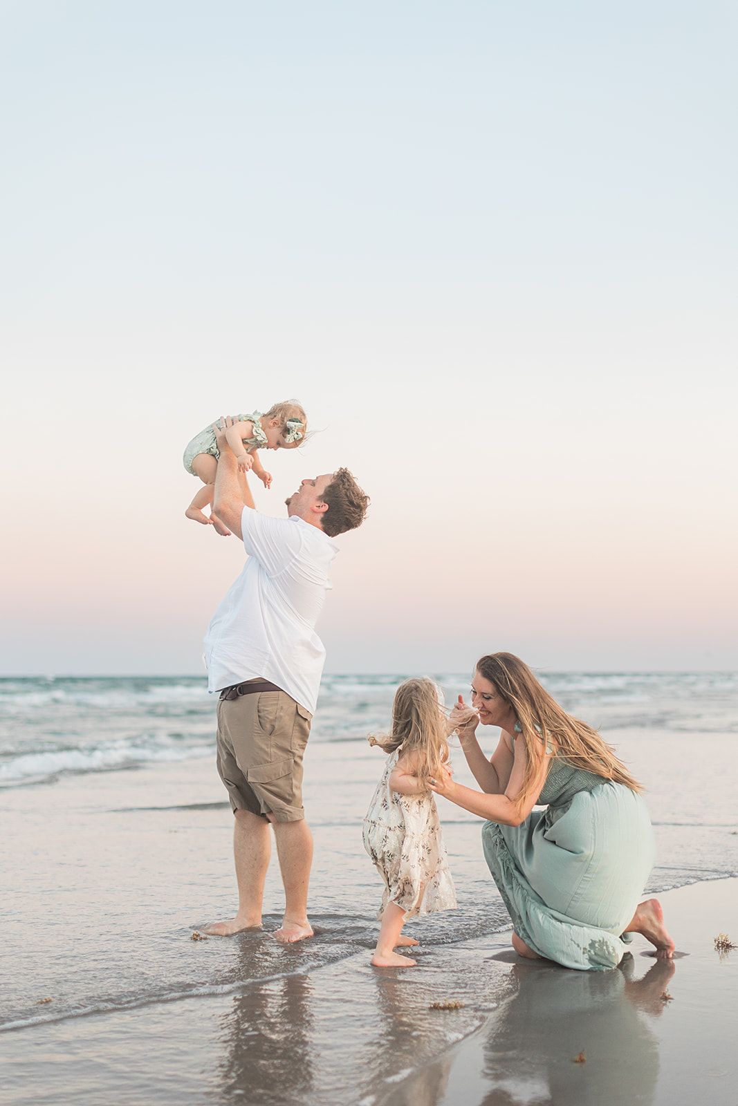 Family of four playing and enjoying a beach photo session in Port Aransas, Texas