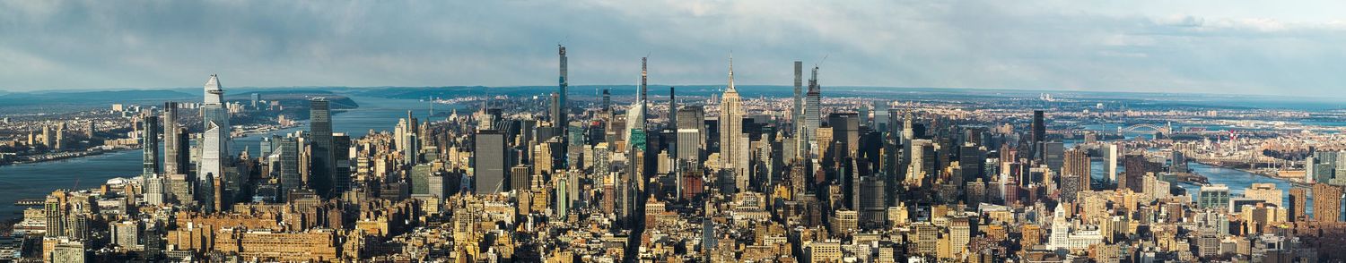 Panoramic cityscape view of a modern metropolitan skyline against blue sky.