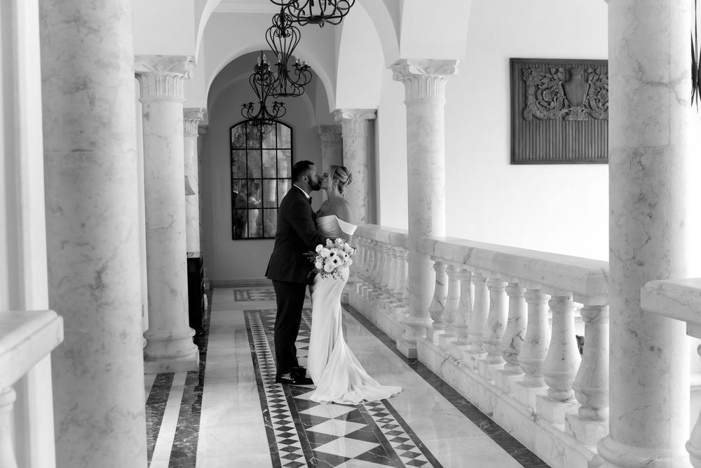 A luxurious white marble colonnade with ornate archways and decorative details extends along a covered outdoor walkway.