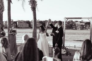 Wedding ceremony setup with white chairs and palm trees along a waterfront venue.