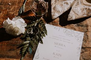 Wedding stationery and greenery styled on vintage wooden surface.