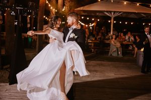 Newlyweds share a romantic dance under warm lighting at their outdoor reception.