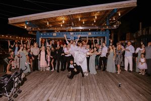 Wedding reception venue with string lights and large crowd of guests.