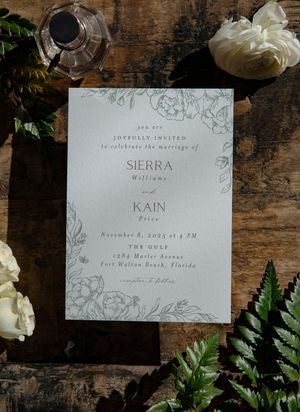 Wedding invitation suite with floral design elements on rustic wooden surface.