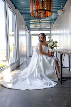 Elegant bridal portraits in white gown against modern blue-ceiling venue.