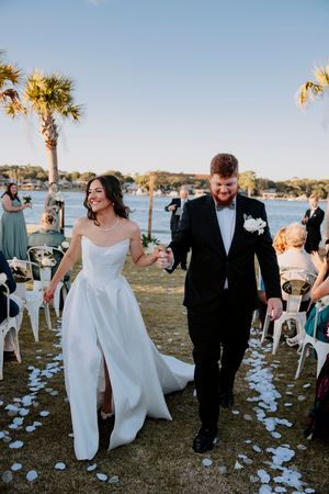 Wedding ceremony exit with white petals scattered along seaside path.