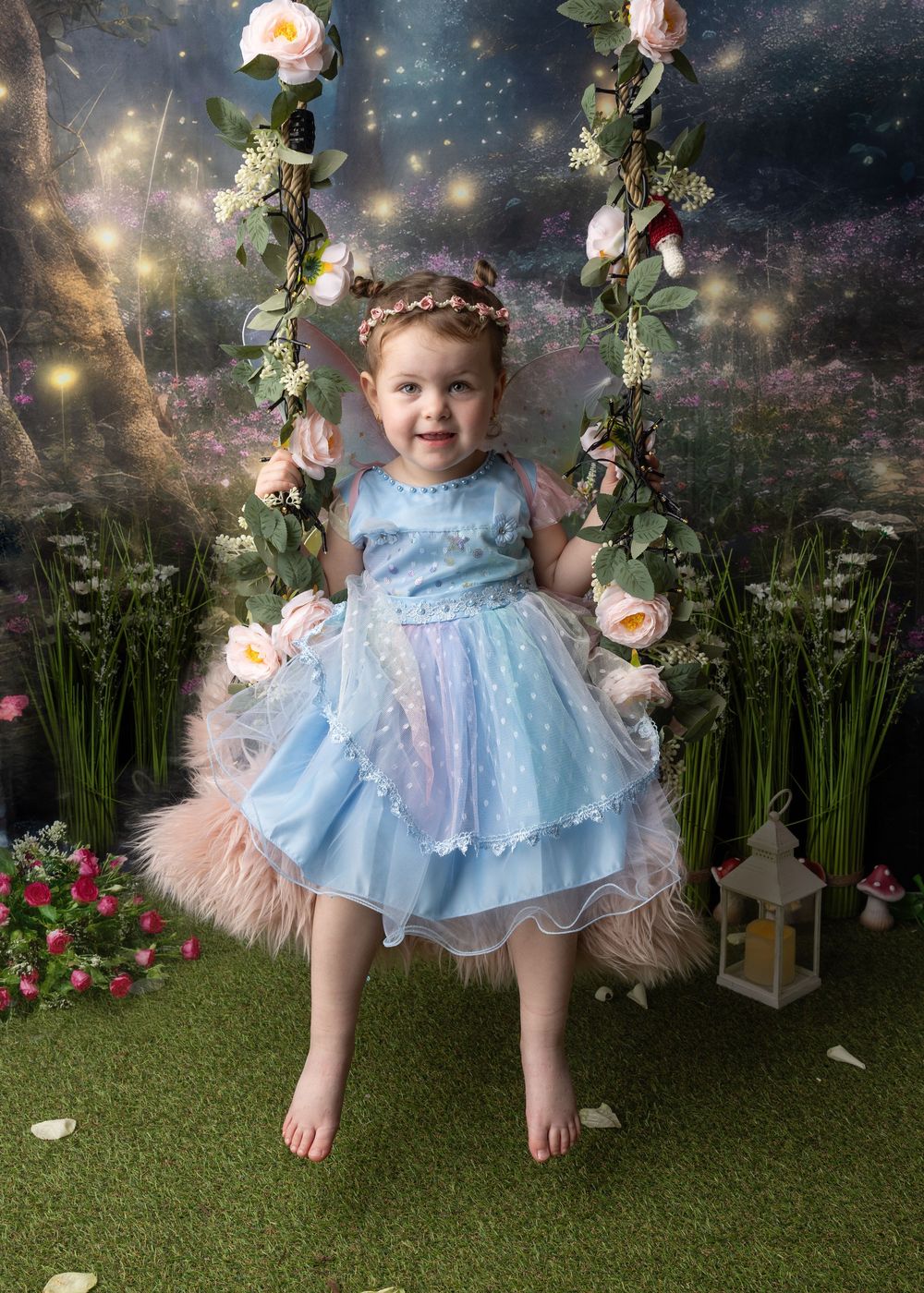 A magical fairy-tale themed photo set with roses, sparkling lights, and a dreamy blue dress against a starry backdrop.