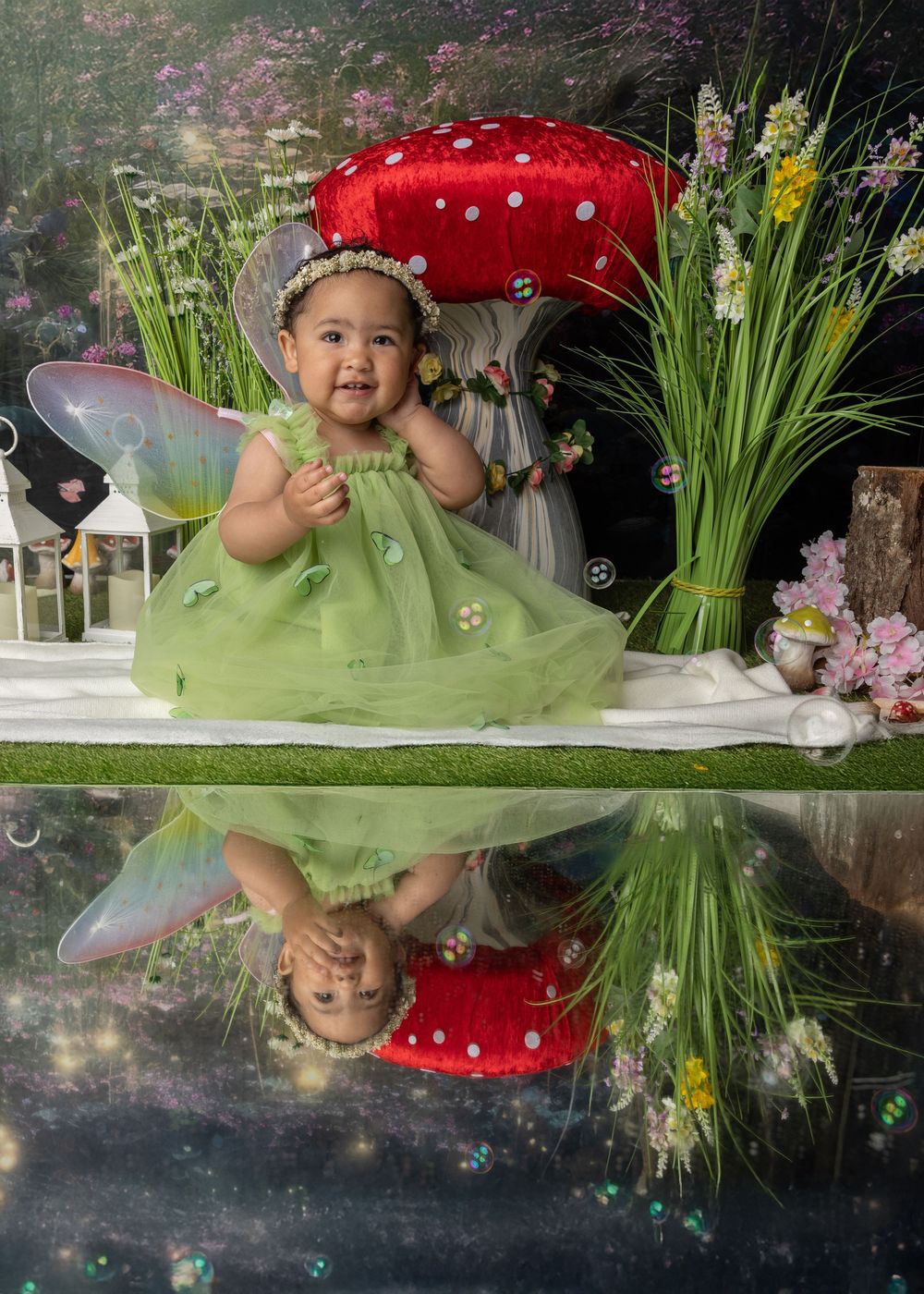 A whimsical fairy garden scene with a large red mushroom, spring flowers, and reflective mirror surface.