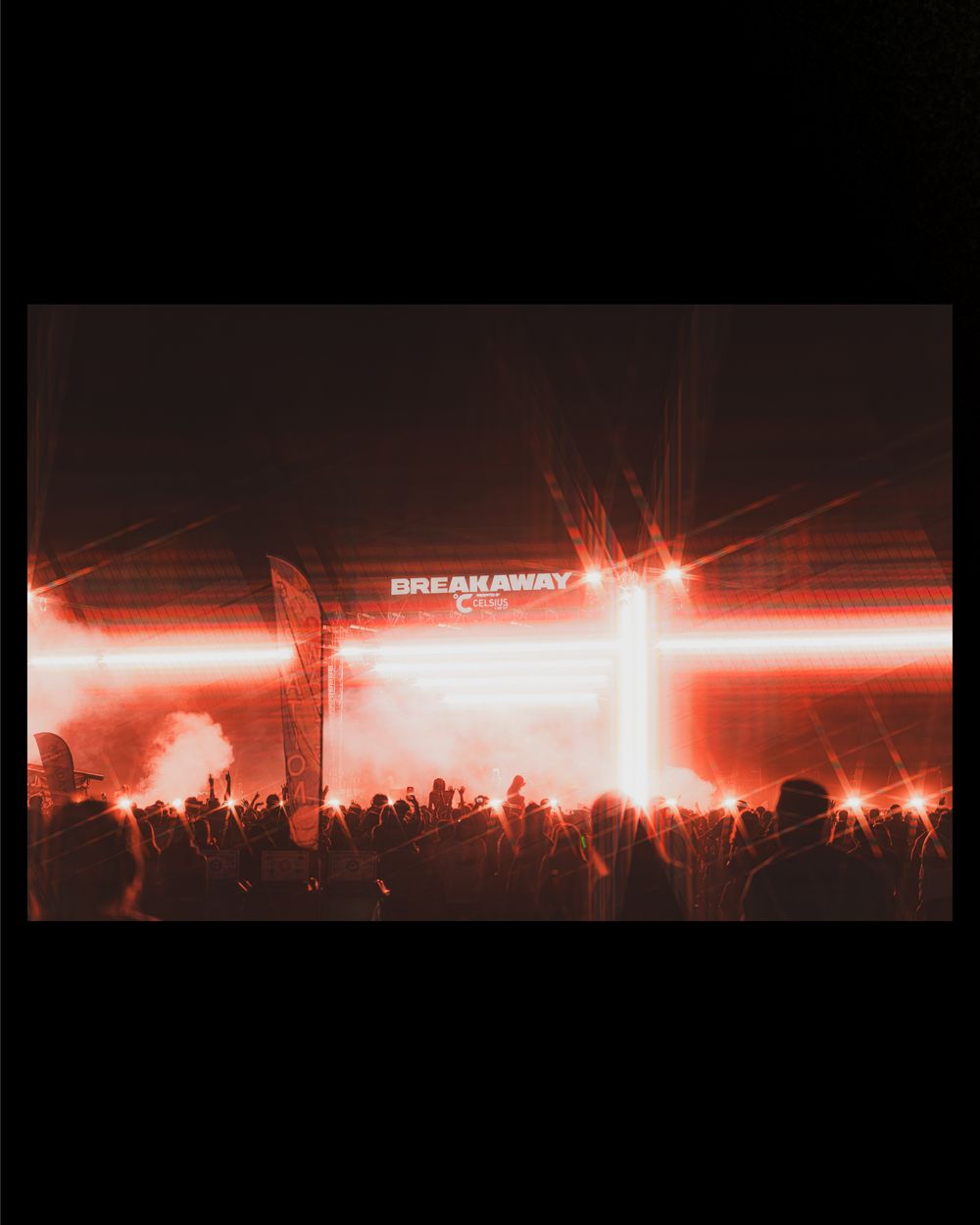 Breakaway music festival stage lit with red lights and lasers, crowd silhouetted against bright beams at night.