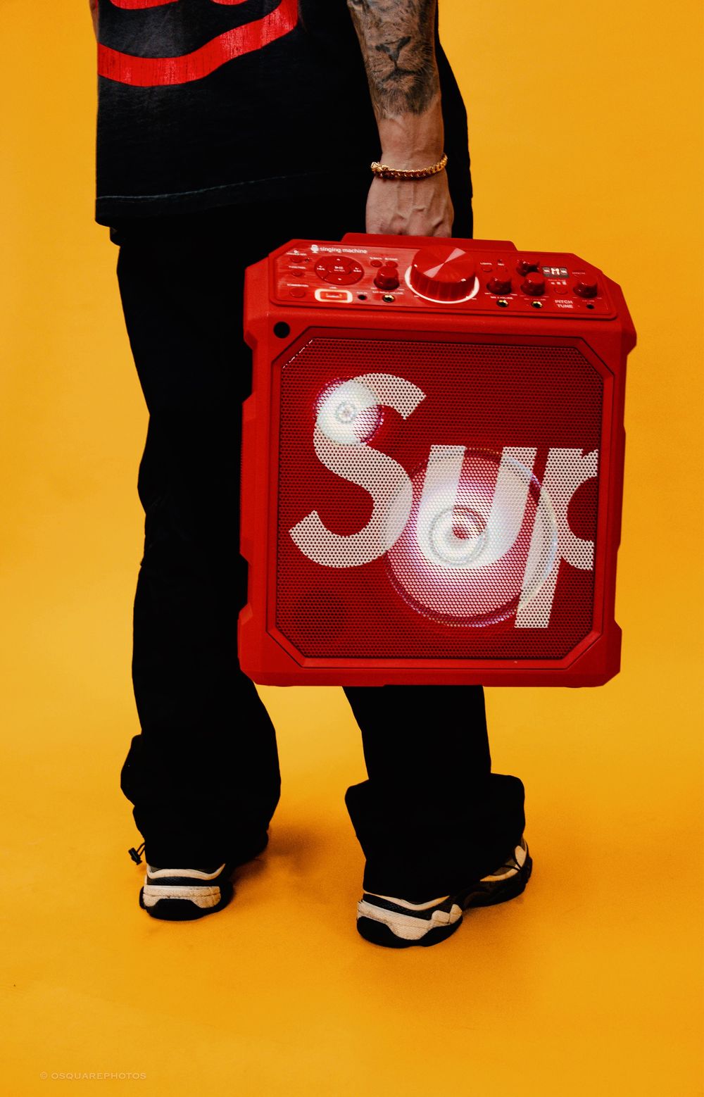Red Supreme cooler photographed against vibrant yellow background with person's legs visible.