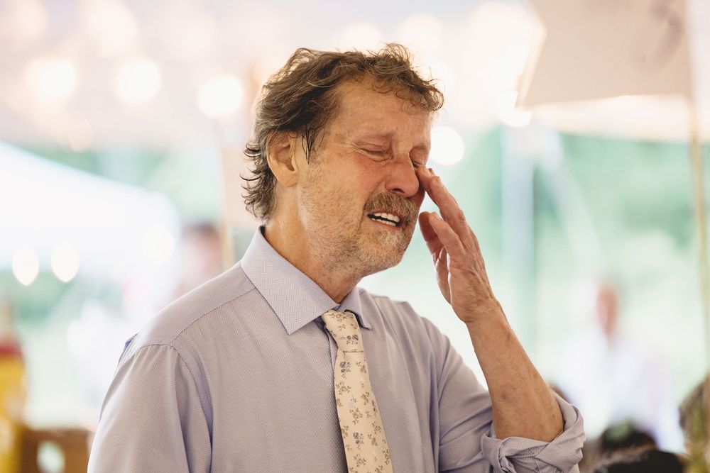 A person in formal attire laughs joyfully during what appears to be a wedding celebration.