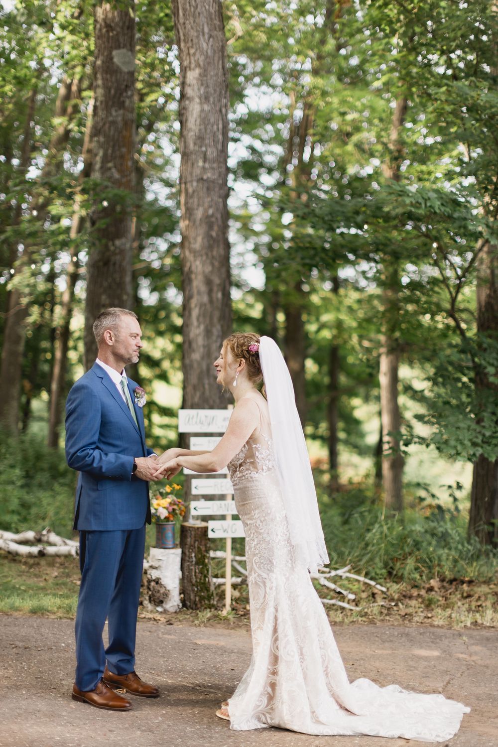 A couple shares their first look moment in a wooded outdoor setting during their wedding celebration.