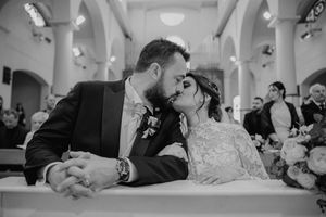 Lo sposo bacia la sposa all’altare della chiesa, in bianco e nero.