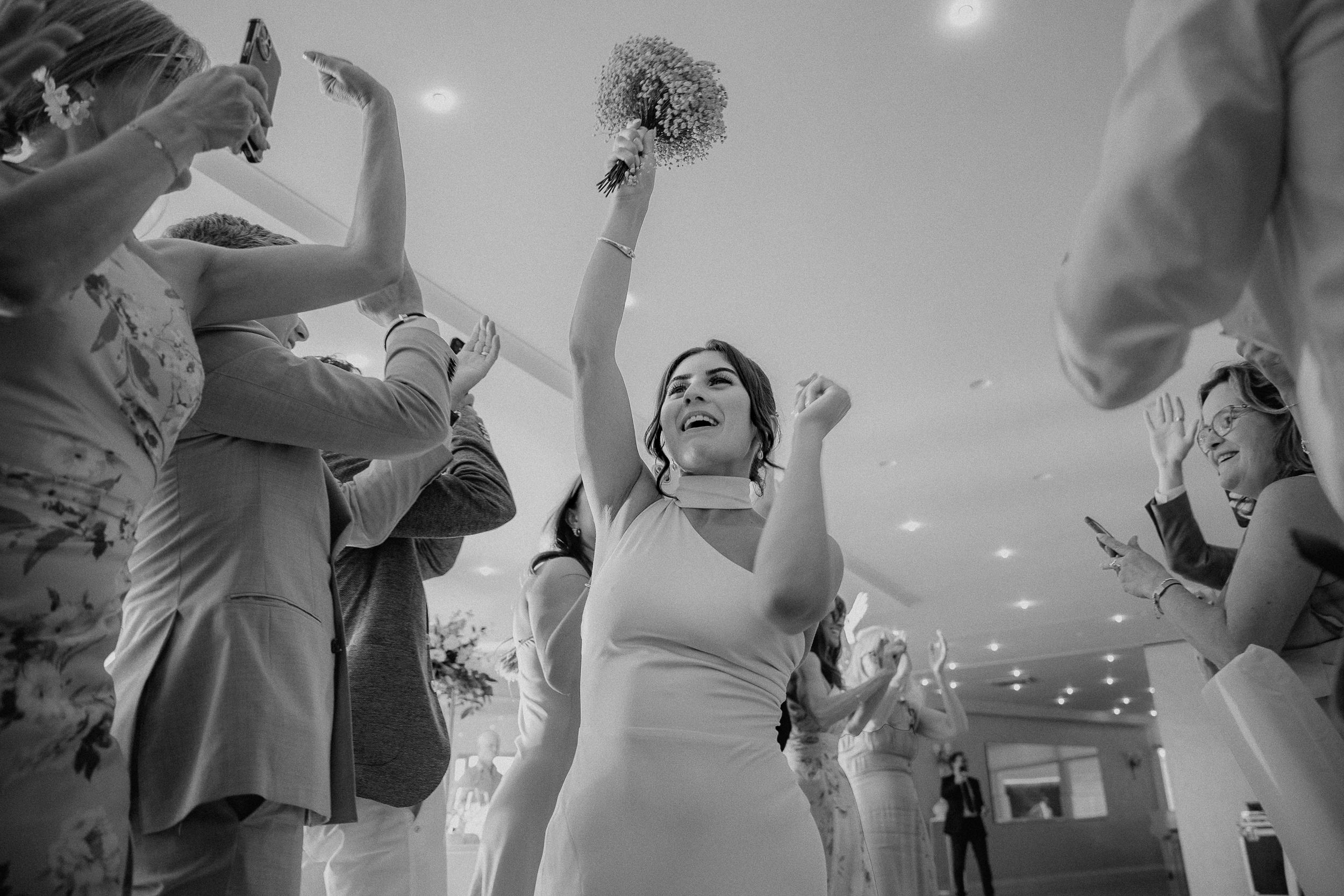 Barbara alza il bouquet durante i balli del ricevimento, in bianco e nero.