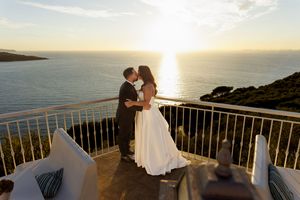 Giuliano e Barbara abbracciati su una terrazza affacciata sul mare al tramonto.