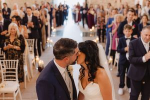 Marco ed Elena si baciano durante la cerimonia, circondati dagli invitati.