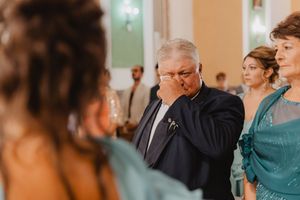 Un invitato si asciuga le lacrime durante la cerimonia, circondato dalle persone care.