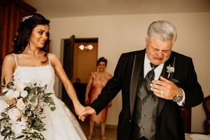 Un padre si commuove vedendo la figlia vestita da sposa e le stringe la mano.