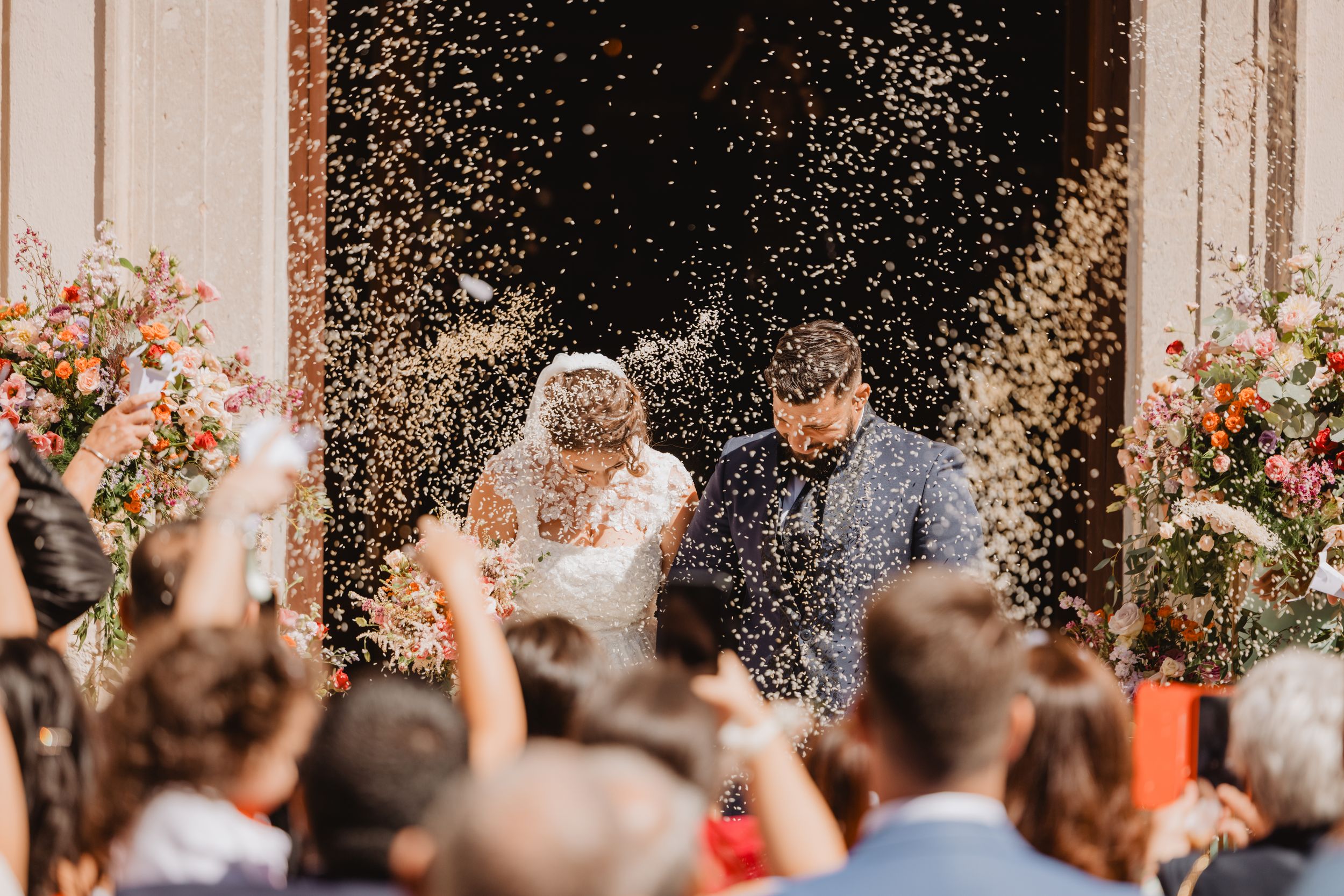Salvatore e Mariarita escono dalla chiesa sotto una pioggia di riso, tra gli invitati in festa.