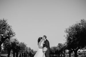 Gli sposi si baciano tra gli alberi, in una fotografia in bianco e nero.