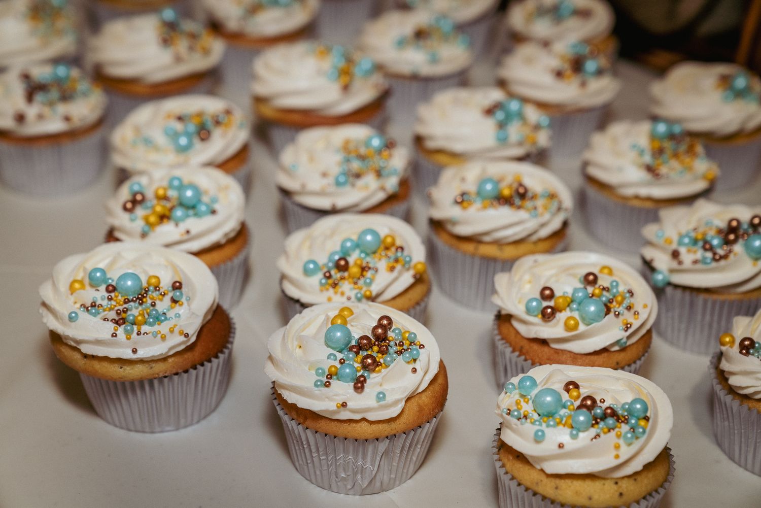 Colorful wedding cupcakes decorated with sprinkles and ocean theme toppers. Sweet reception details.