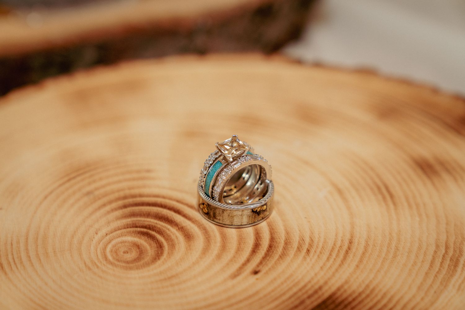 Wedding rings displayed on wooden tree ring slab. Rustic and elegant wedding detail shot.