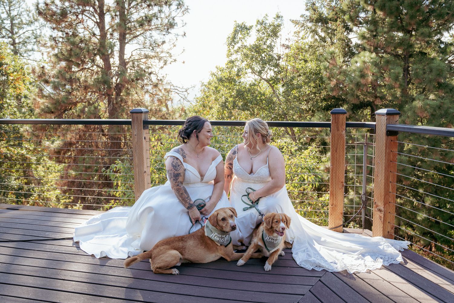 Lesbian couple with dog relaxes post-ceremony on wooden deck, Oregon.