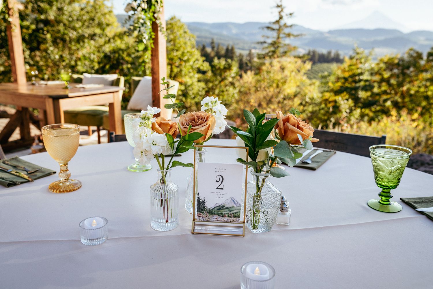 Elegant wedding table setup with florals, table number, and Oregon mountain views. Outdoor reception decor.
