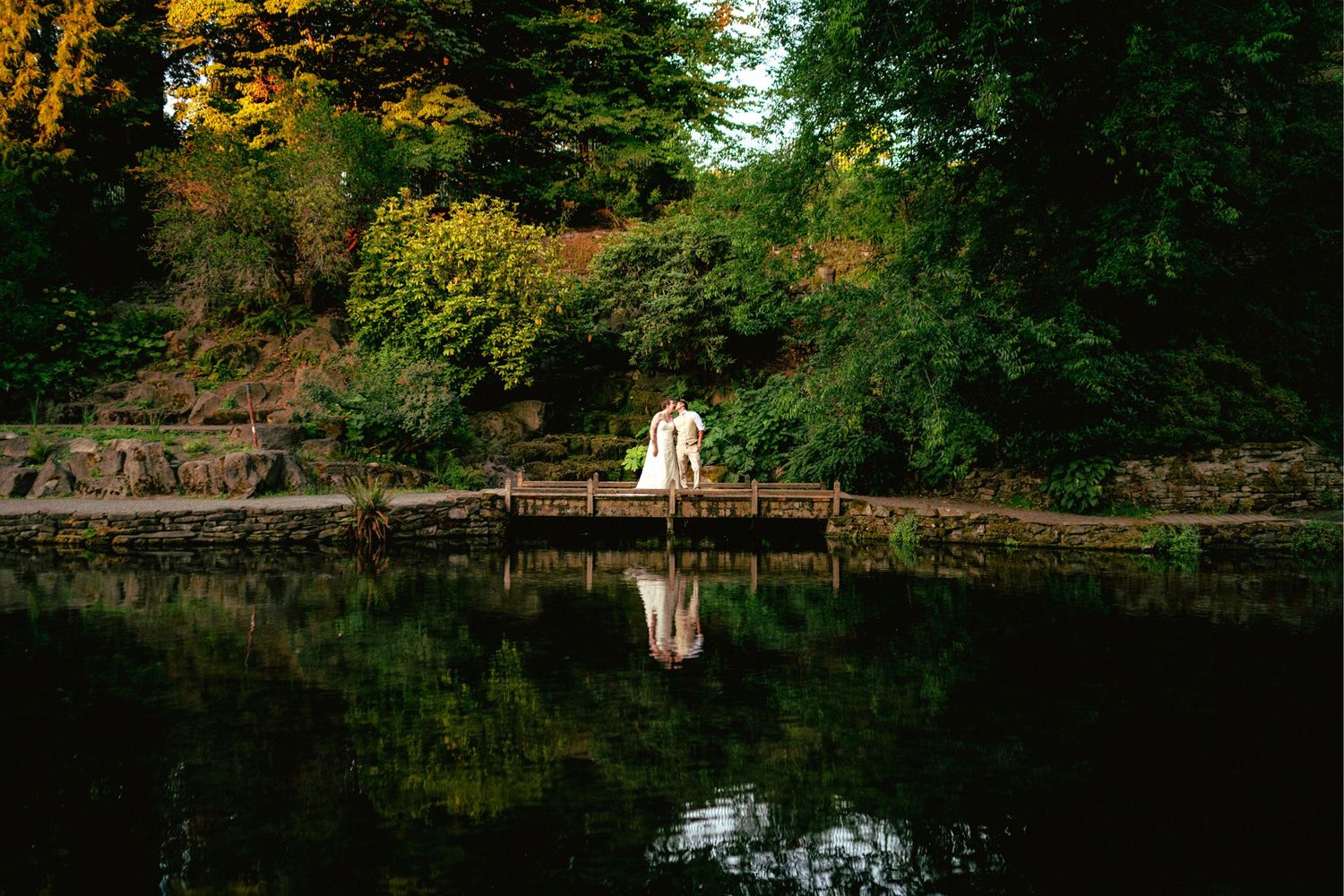 Bride and groom sharing a romantic moment on a dock surrounded by lush greenery of PNW and a calm reflective lake.