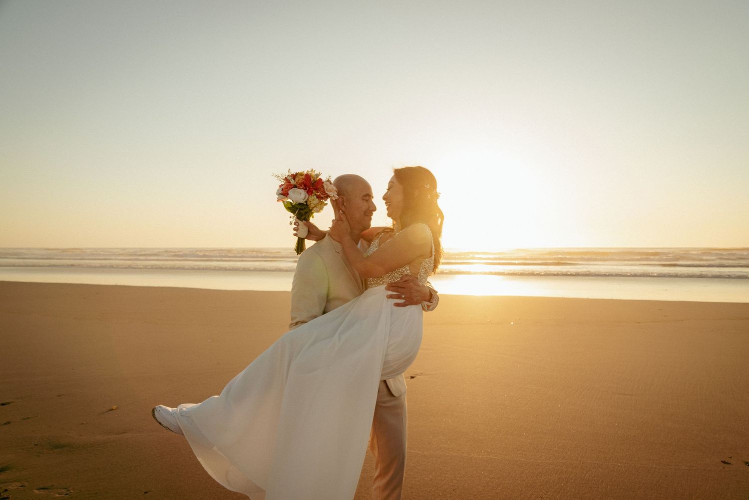 Couple embracing at sunset on the Oregon Coast, bathed in golden light during a romantic beach wedding.