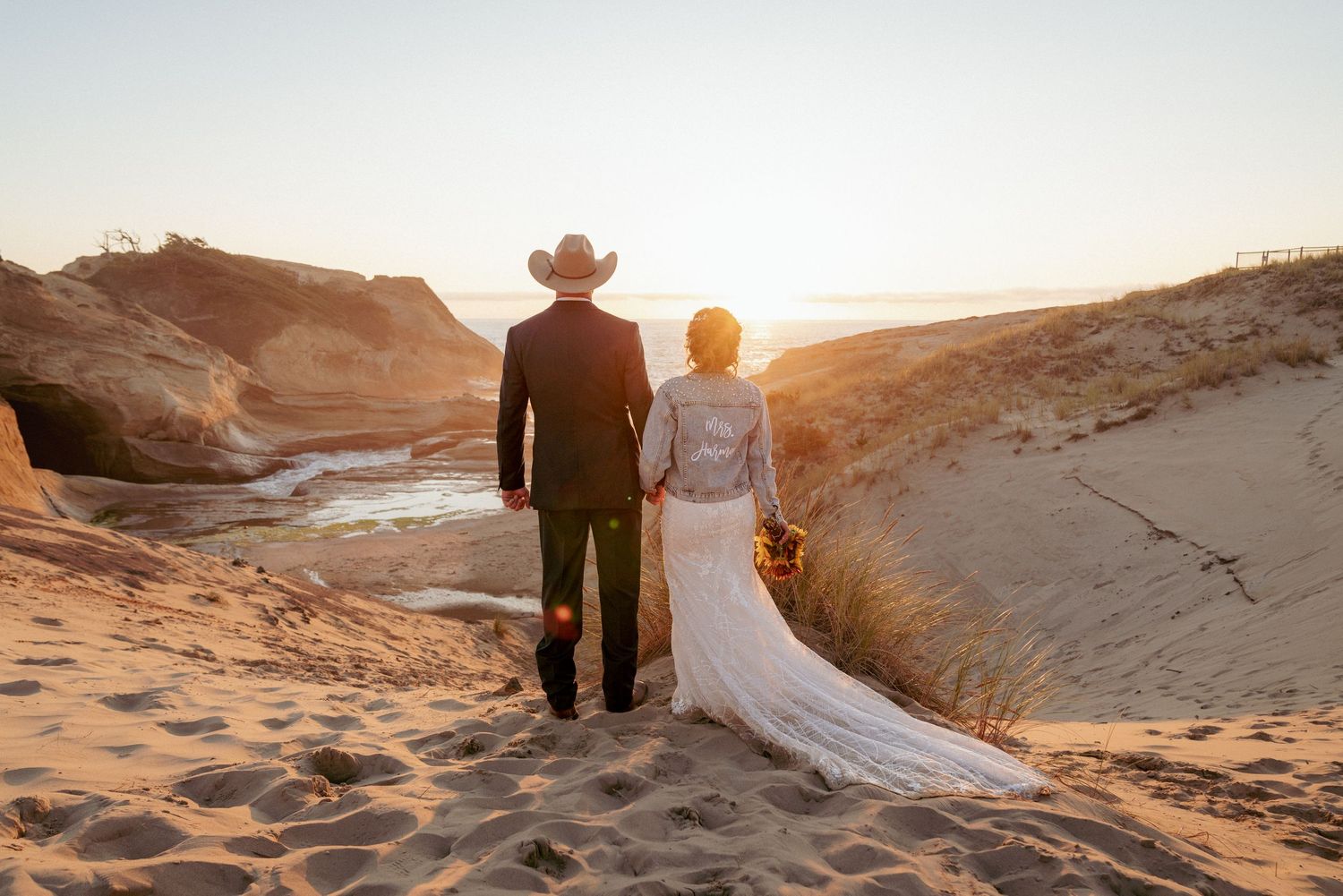 Couple walks Oregon dunes at sunset, cowboy wedding in the PNW.