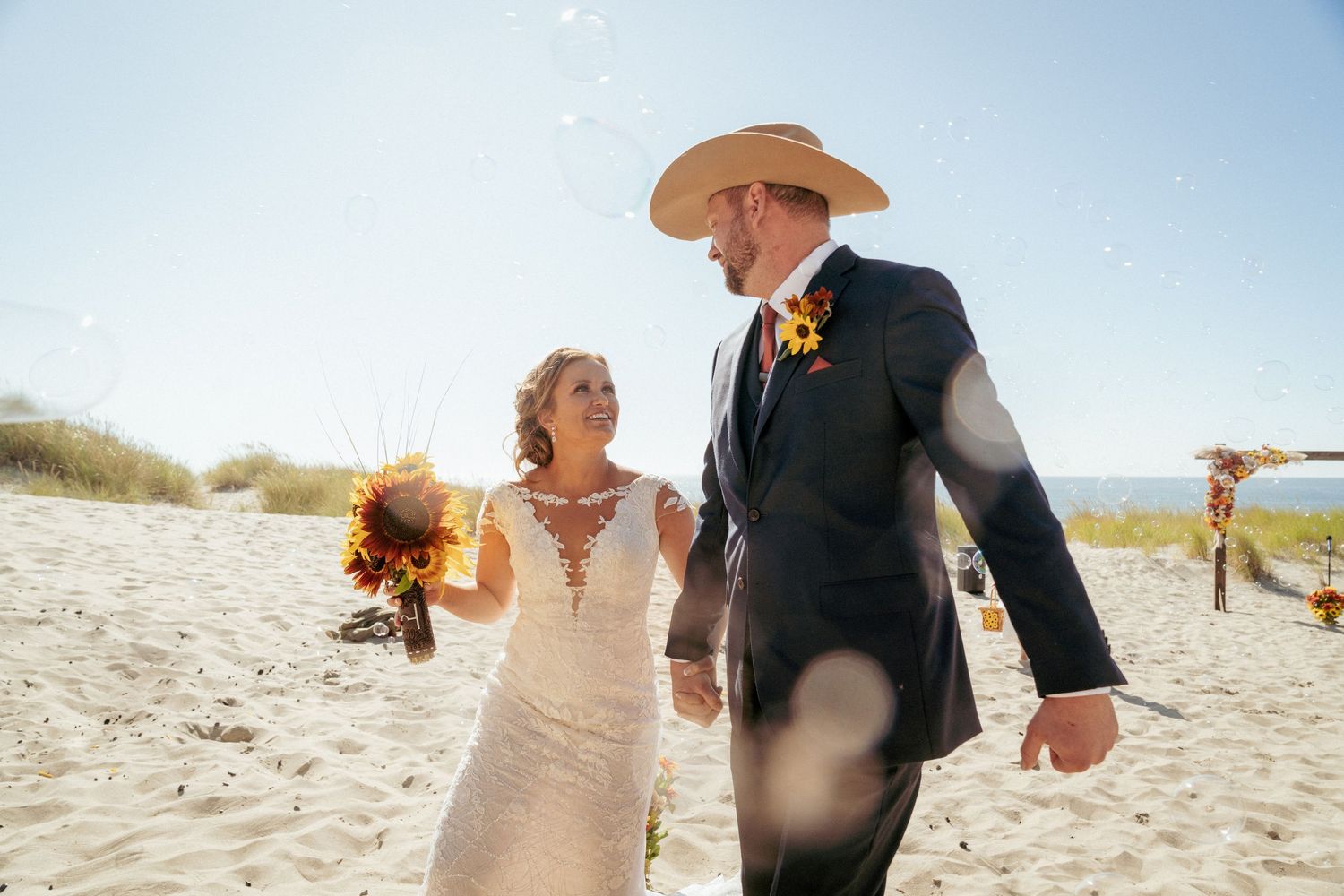 Mixed-race couple walks down sandy aisle, coastal Oregon ceremony.