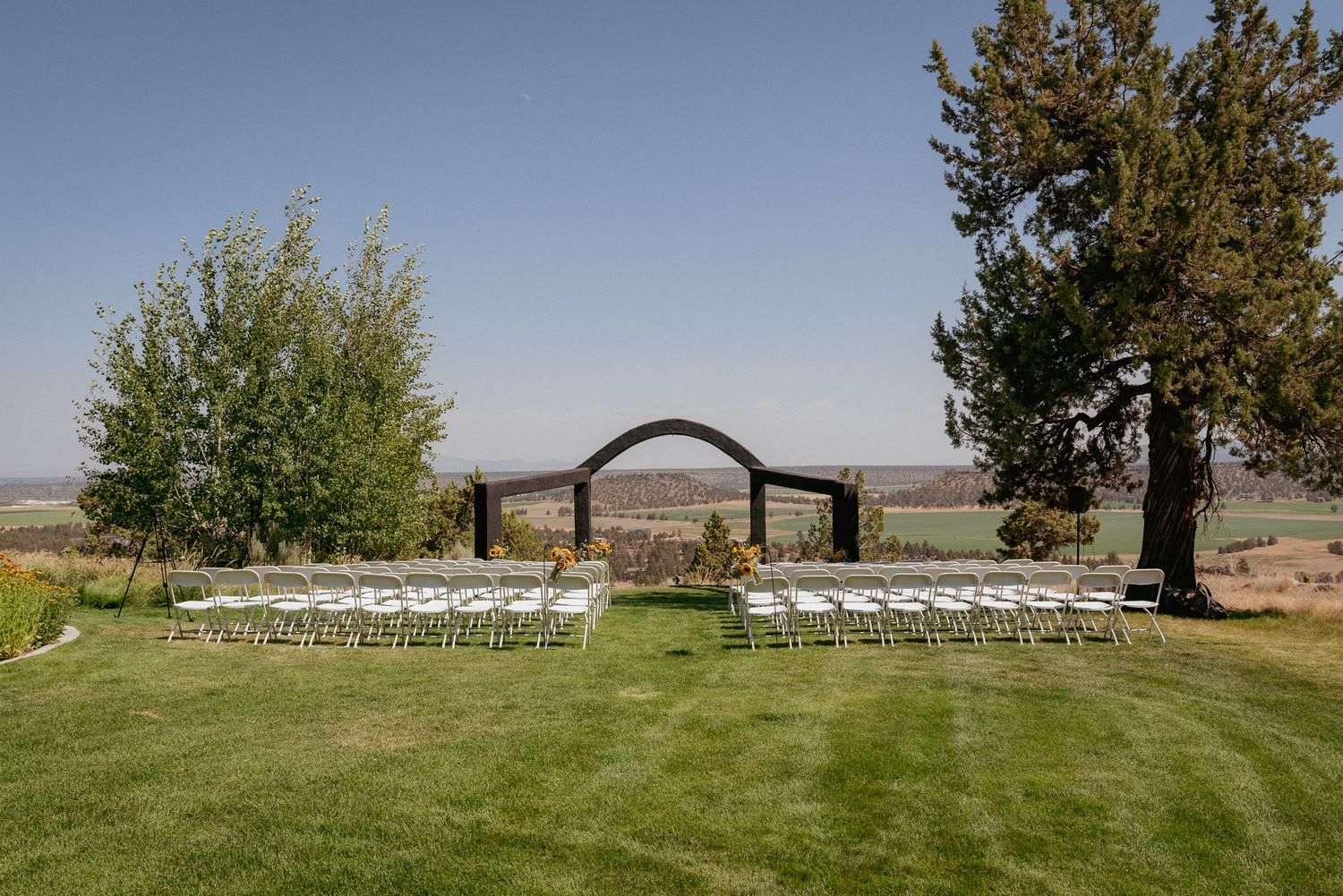 Central Oregon wedding ceremony setup with modern black arches and no guests. Scenic outdoor venue with elegant details.