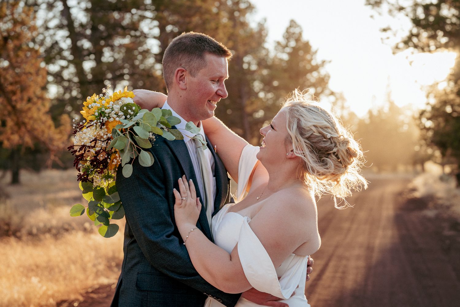 Joyful bride and groom embrace in golden hour light after their Bend Oregon outdoor wedding ceremony.