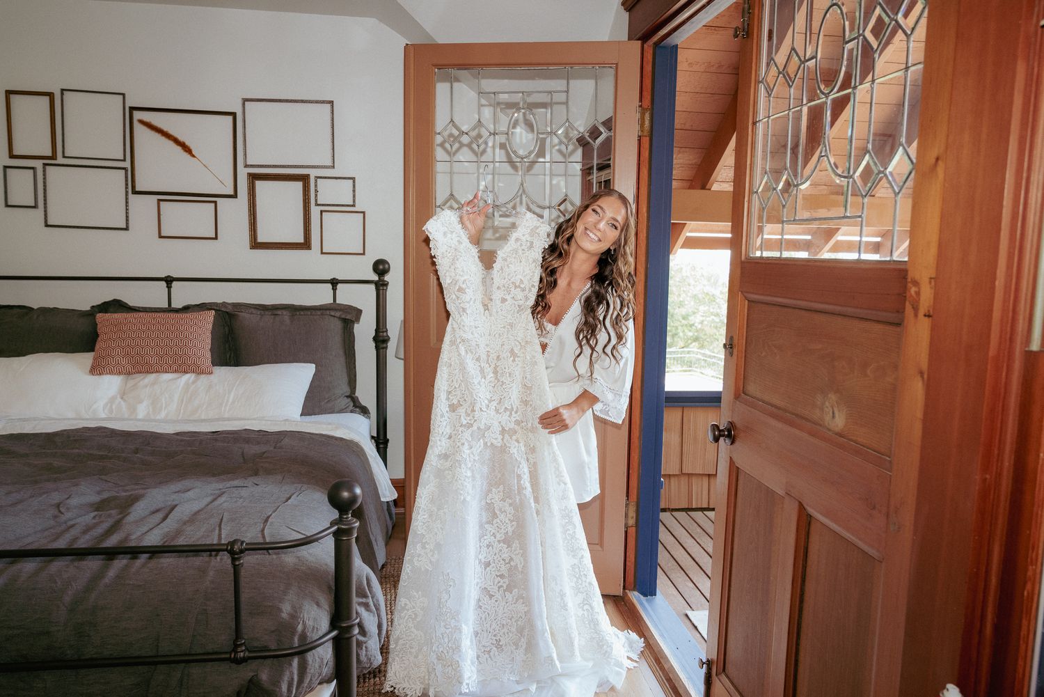 Bride joyfully getting ready in bedroom wearing her wedding dress.