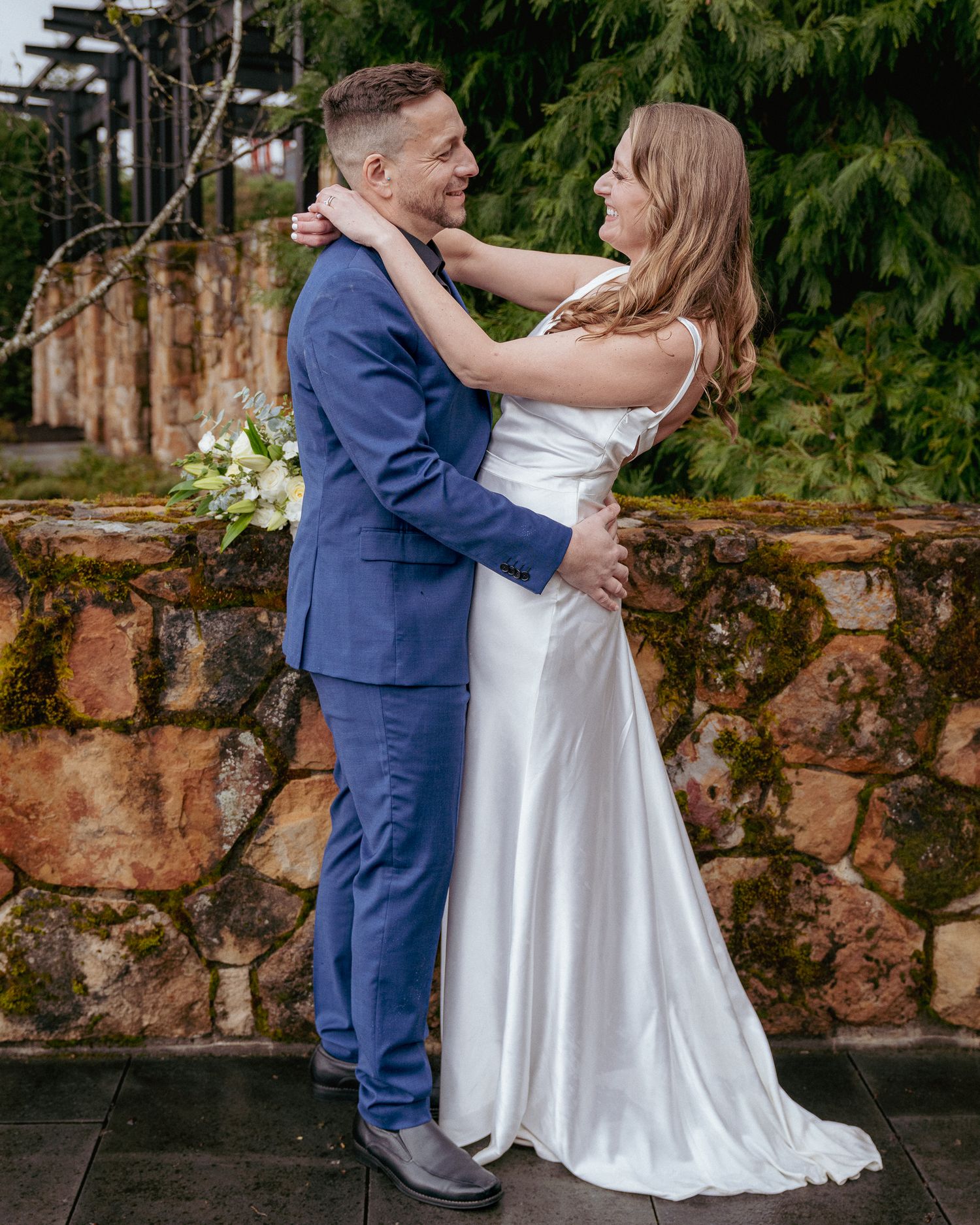 Groom and bride, embracing and looking into each others eyes during rustic outdoor wedding vibes.