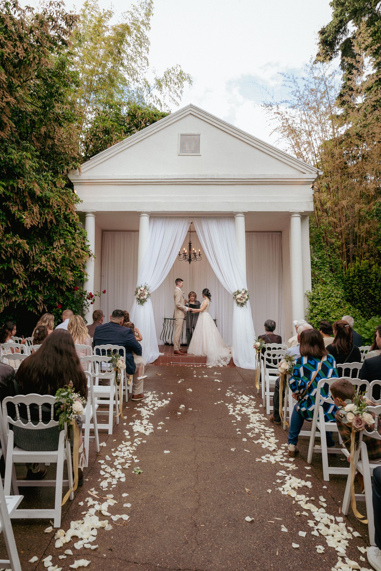 Elegant outdoor garden wedding ceremony with rose petals lining the aisle at a romantic venue in Oregon.