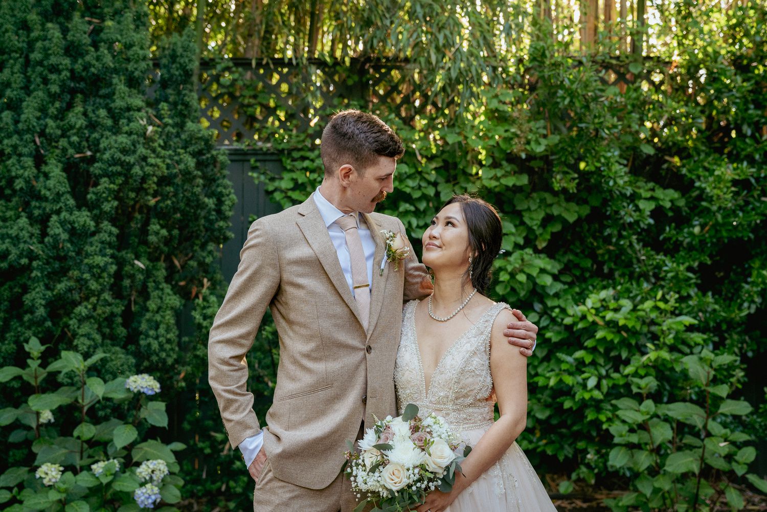Bride and groom laugh in forest, Oregon garden wedding joy.