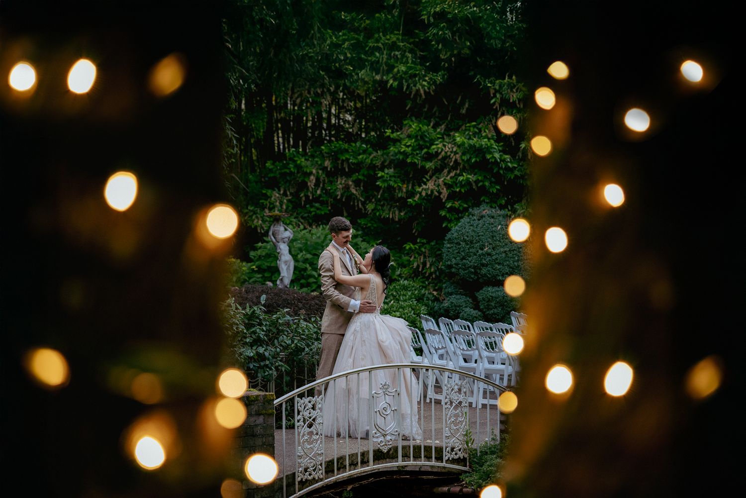 Interracial couple kissing under twinkle lights, Oregon forest wedding.
