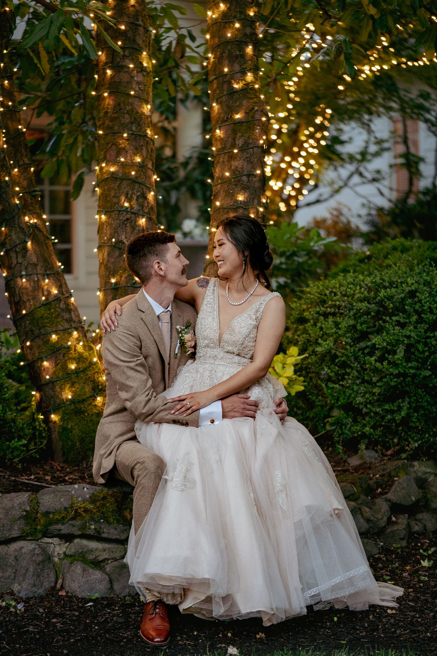 Bride and groom share an intimate moment under twinkling lights in a cozy, quiet wedding setting.