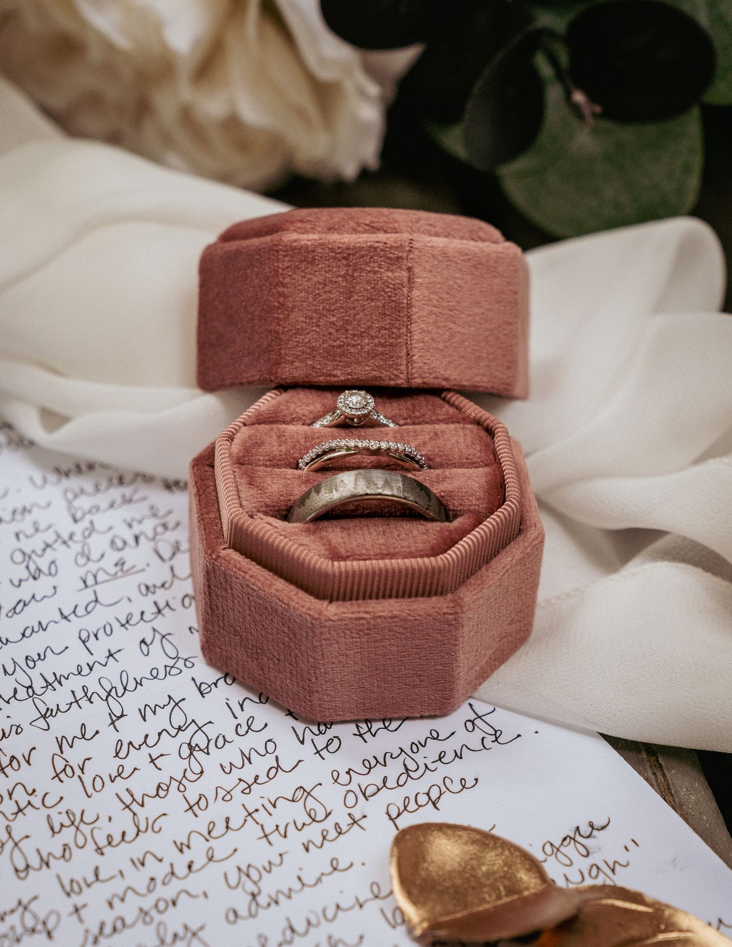 Wedding rings in velvet box placed on handwritten vows for detail shot.