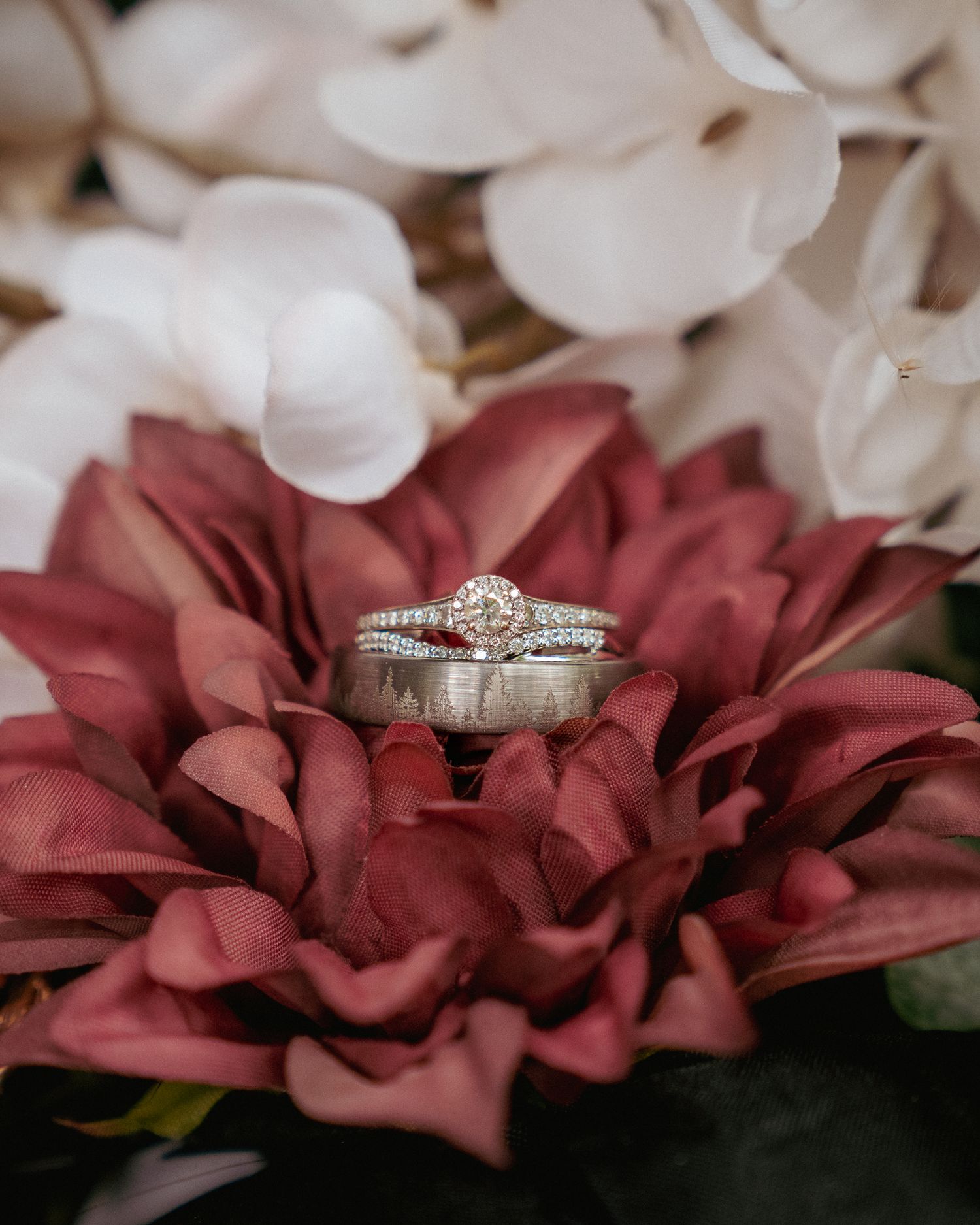 Wedding rings on deep red petals, romantic PNW detail flat lay.