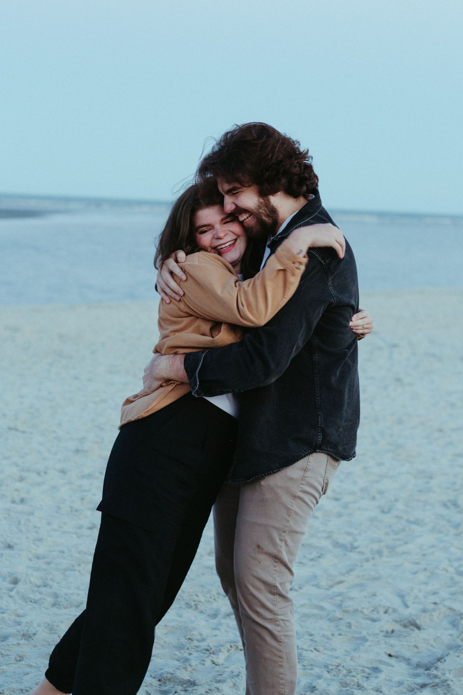Couple embracing on beach during blue hour.