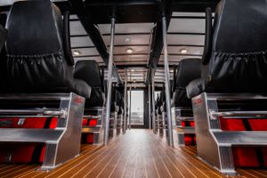 Modern ferry interior with rows of comfortable passenger seating and wooden flooring.